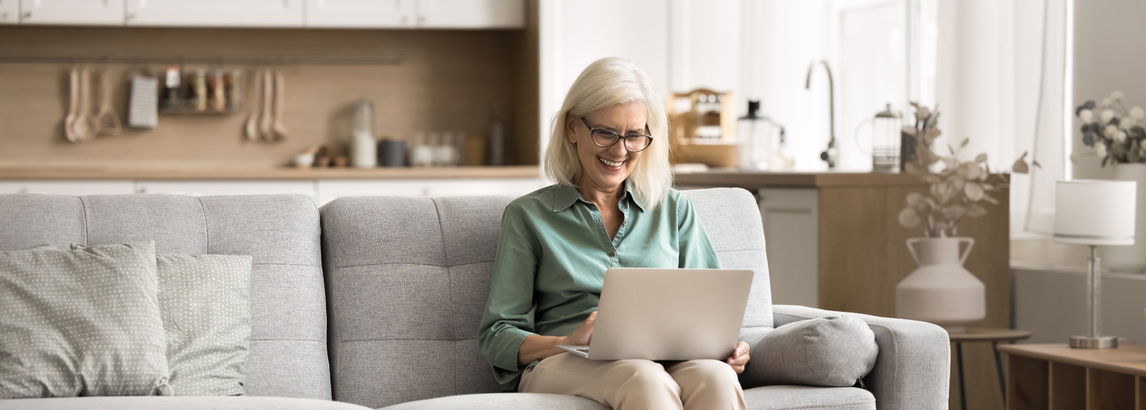 Happy retired woman using a laptop on her couch
